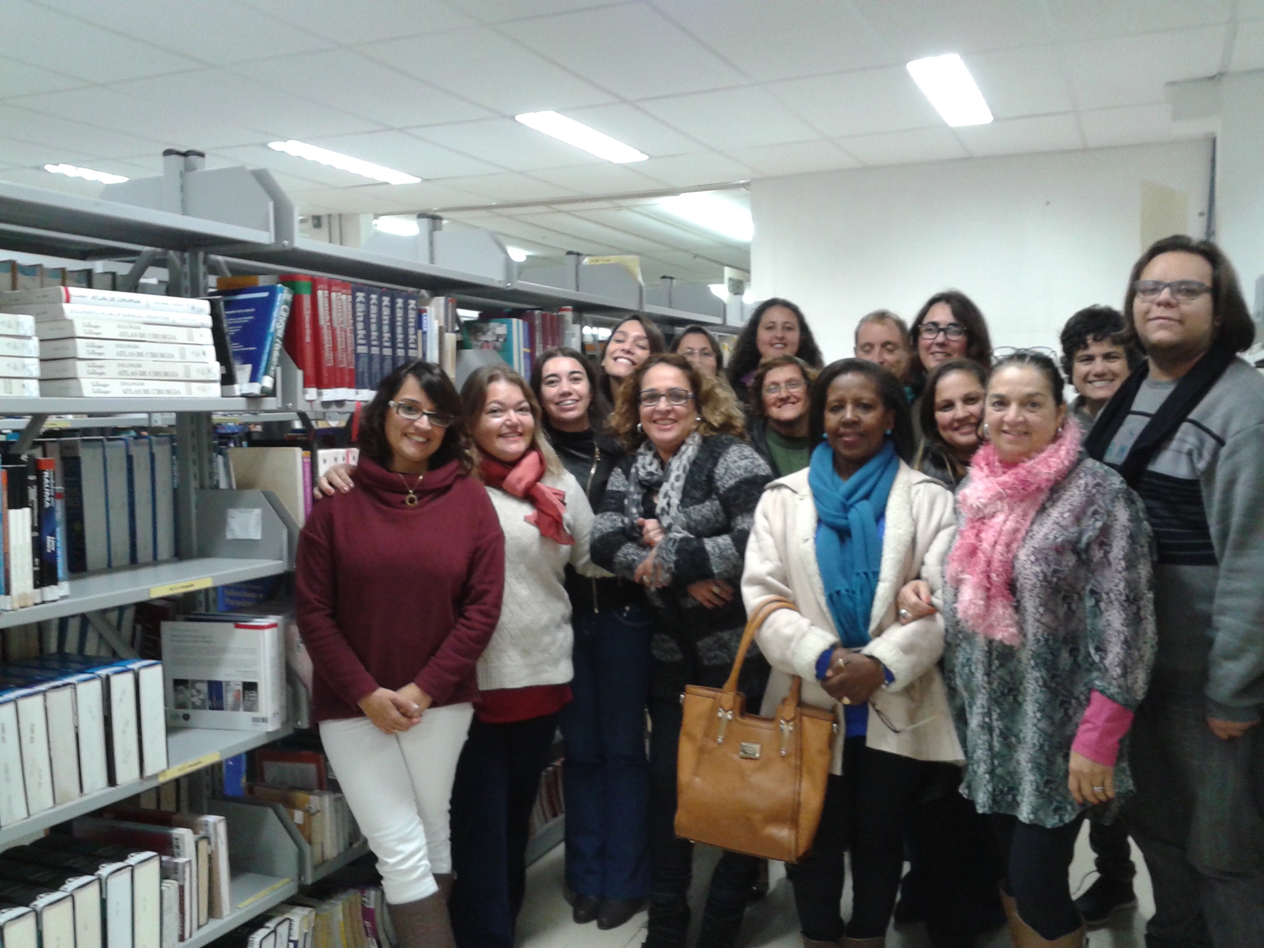 foto da equipe da biblioteca Setorai da área acadêmica da saúde. a equipe está na biblioteca ao lado de uma estante de livros
