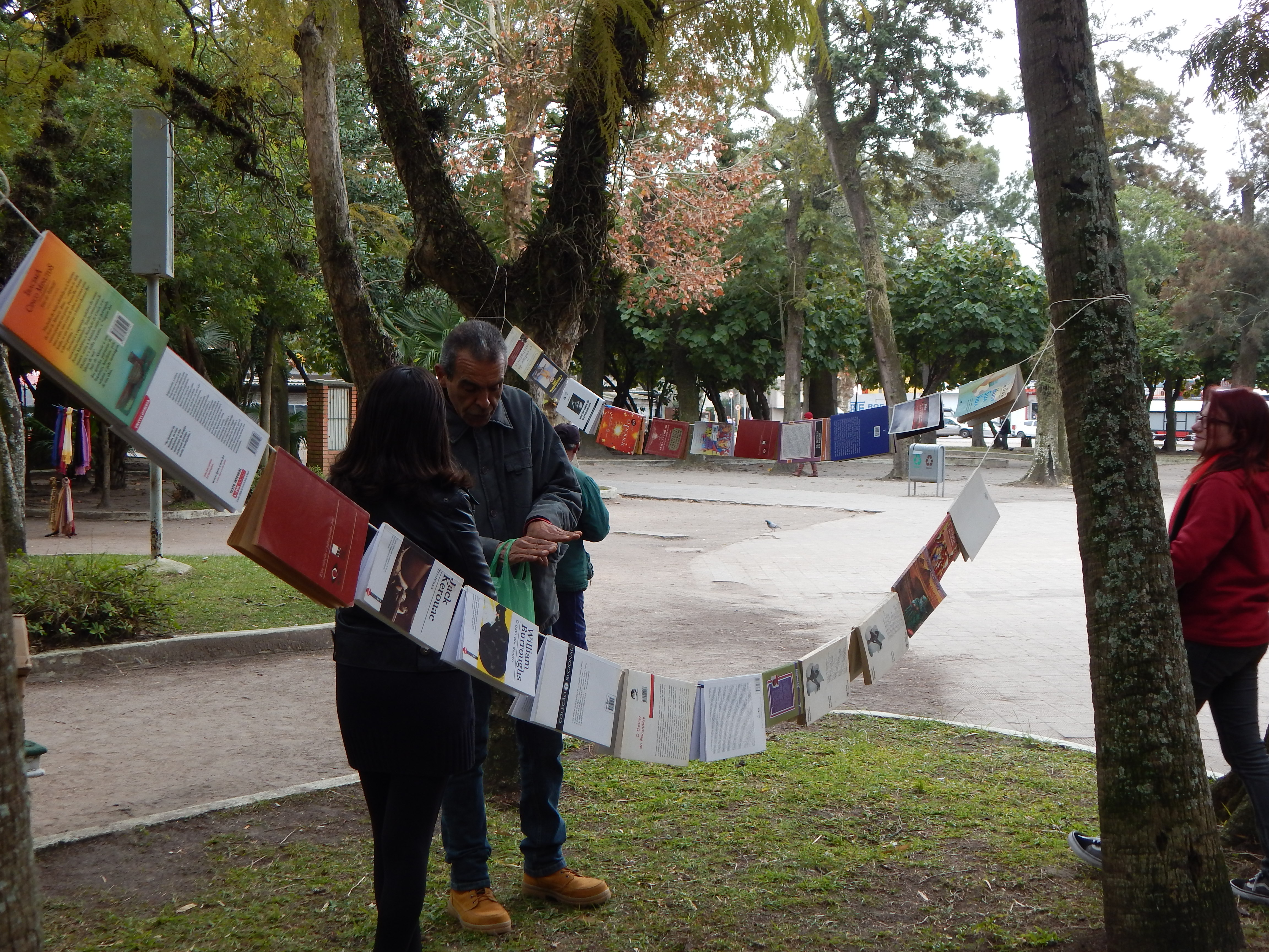 a imagem mostra duas pessoas conversando no meio de um varal de livros na praça tamandaré