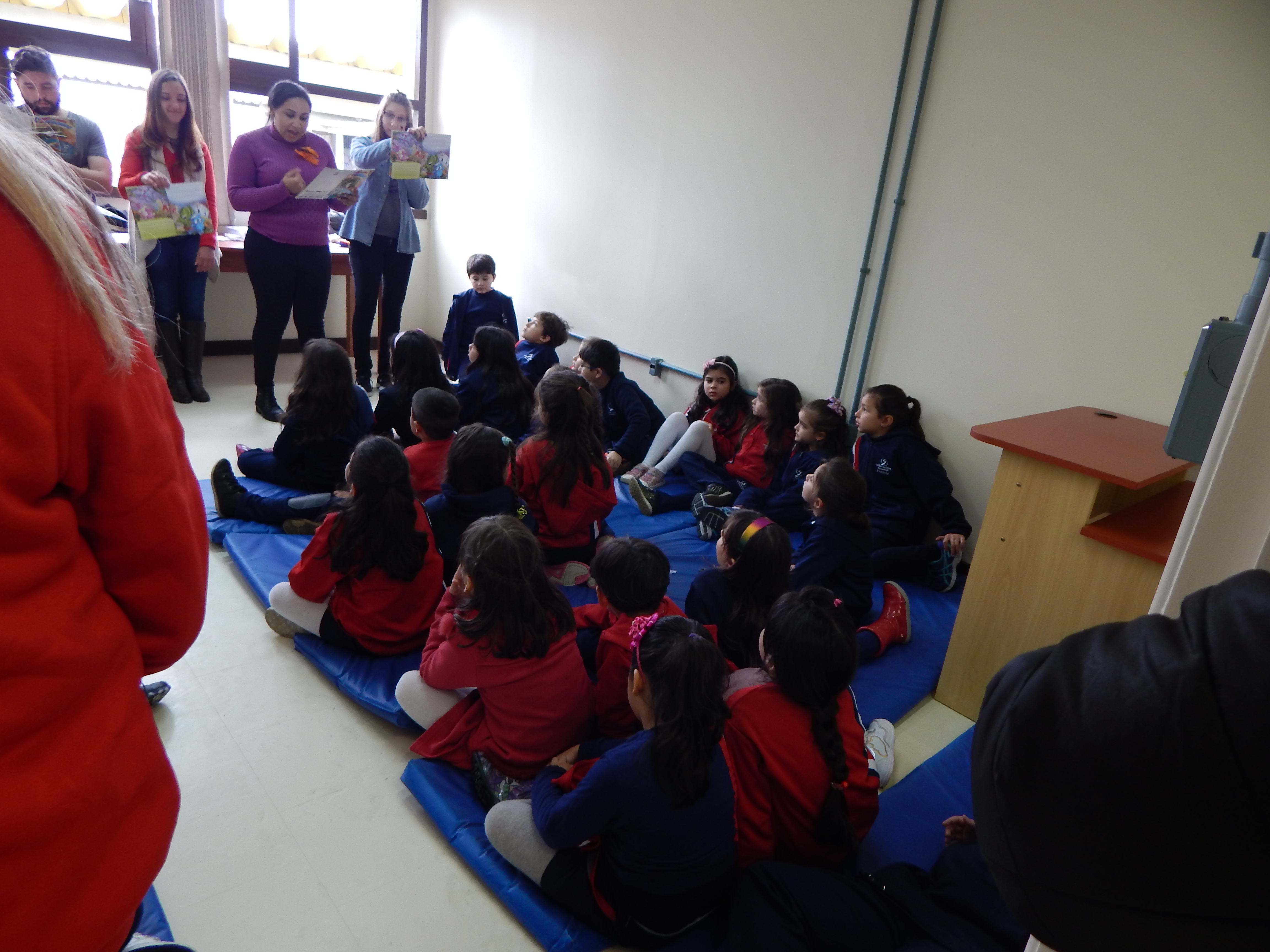 foto em uma sala da biblioteca com alunos do primeiro ano do colégio salesiano sentados em colchonetes escuntando a leitura dos alunos do curso de letras da furg