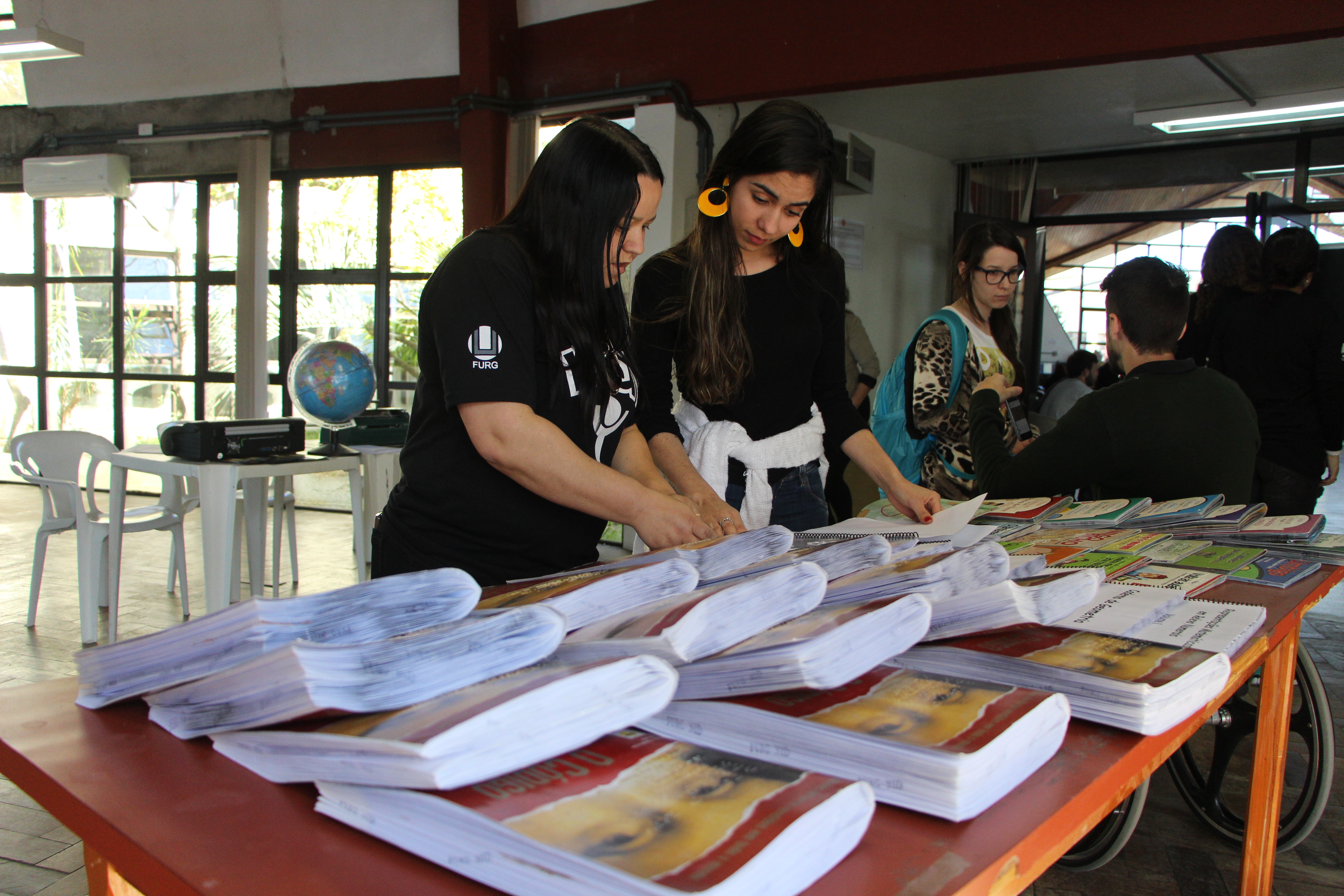 alunas da universidade federal do Rio Grande olhando livros em braille expostos para divulgação no 8º encontro da diversidade